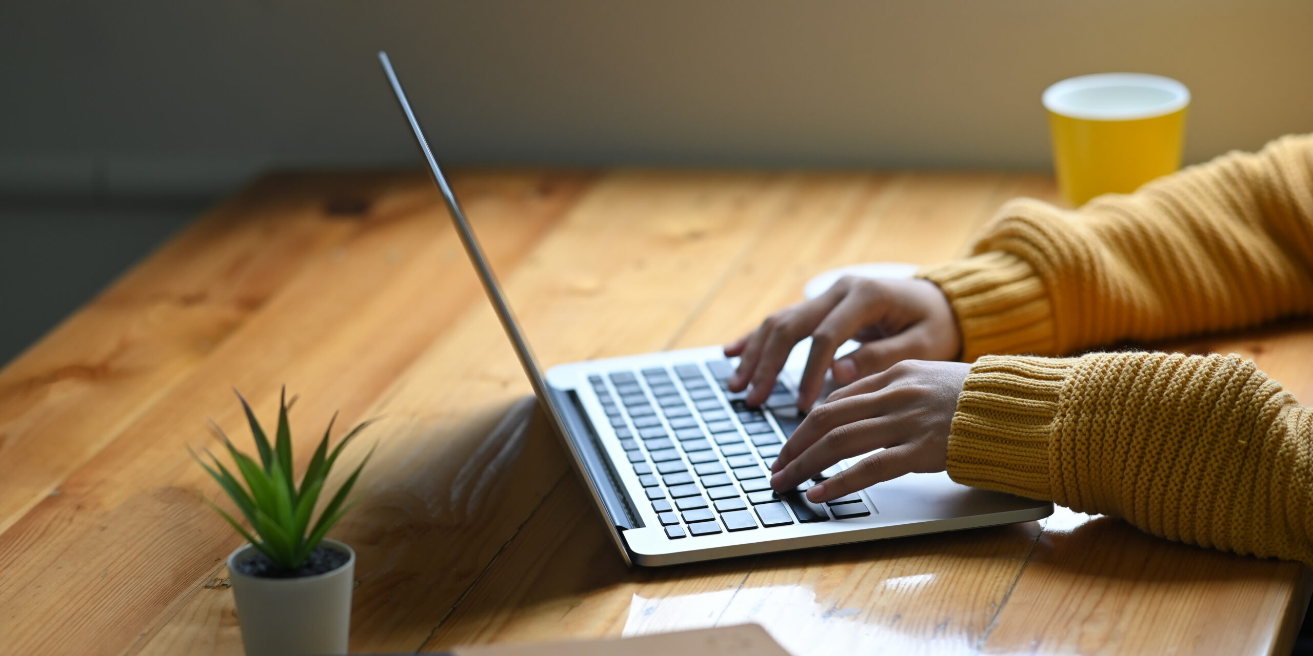 Rising senior working on the Common Application at a wooden desk during the pre-August 1 sprint, typing on a laptop while preparing essays and college list materials before the August 1 Common App opening date.