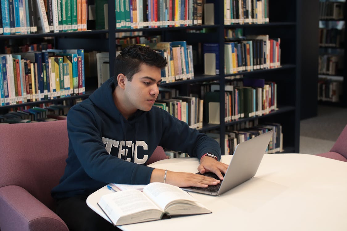 Student researching colleges on a laptop in a university library