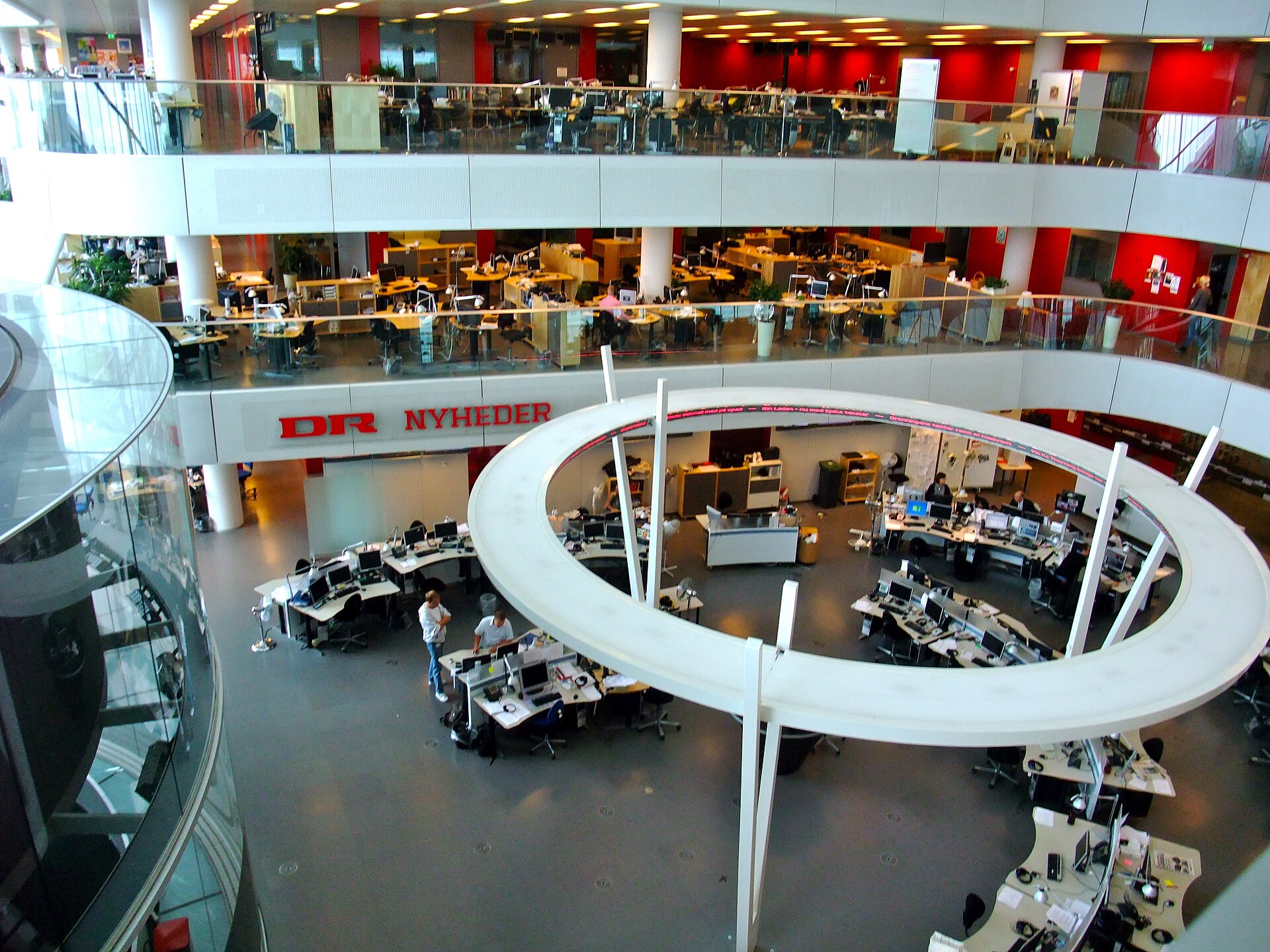 Journalists at work in a large open newsroom