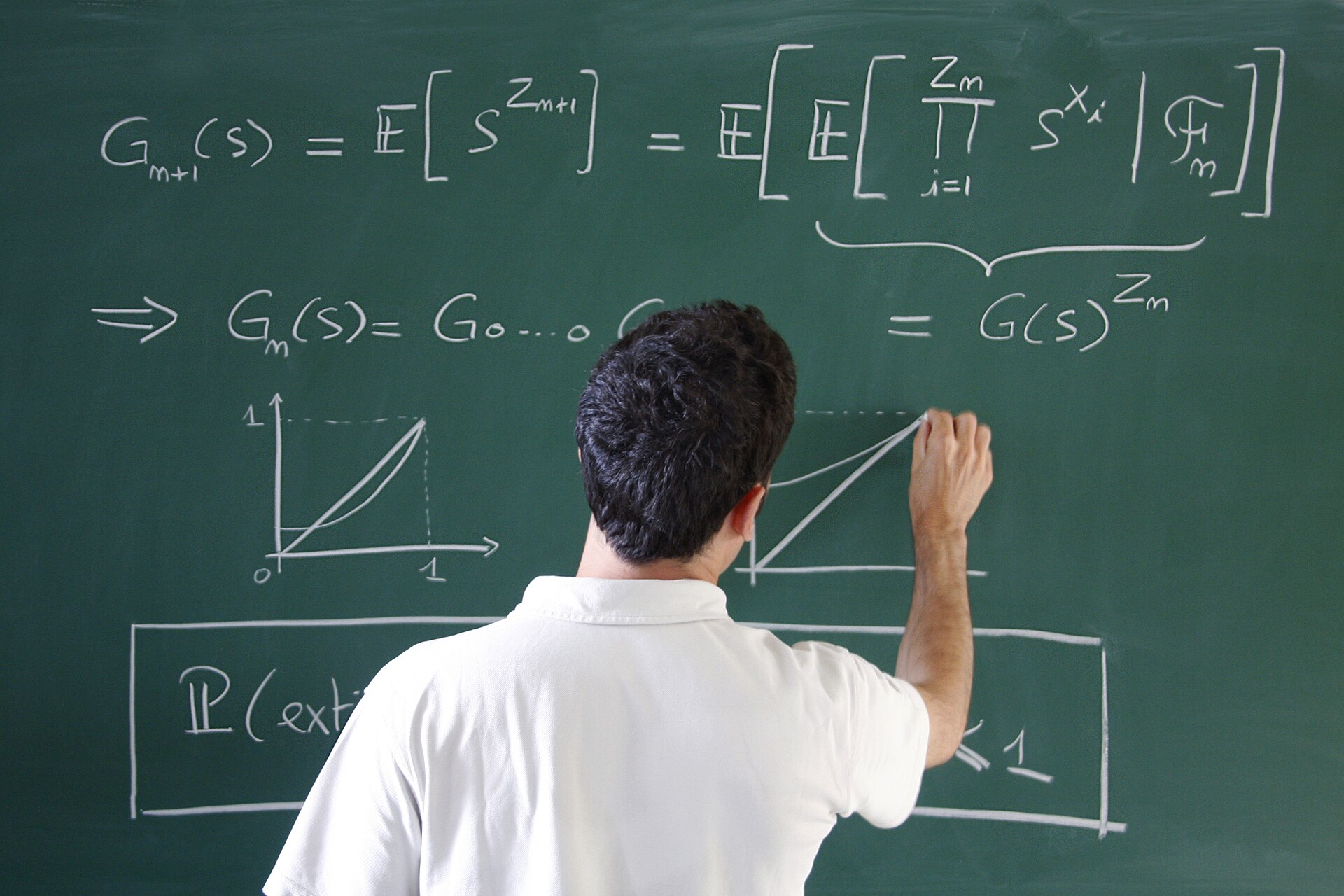 A mathematician writing equations on a green blackboard