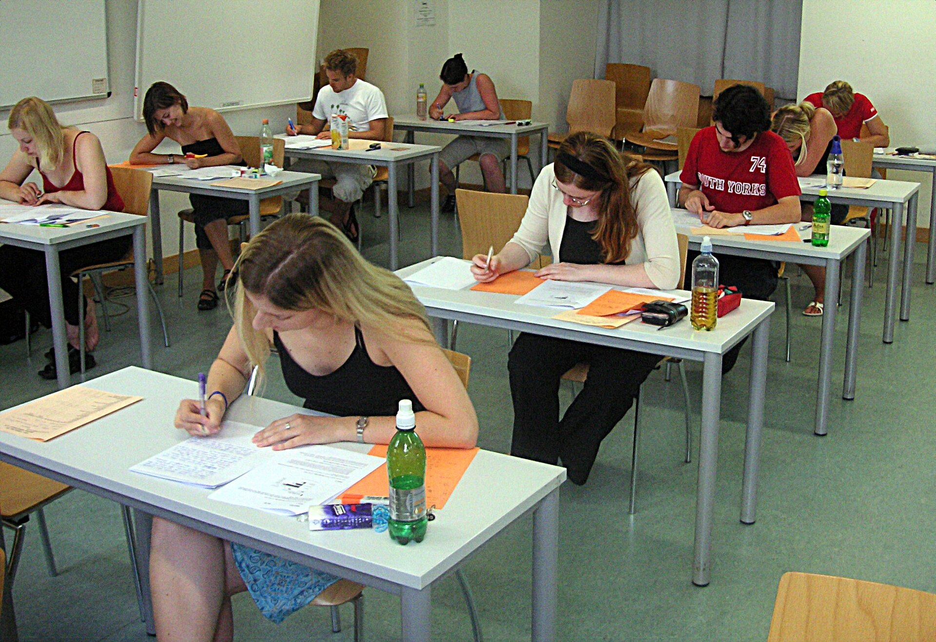 Students seated at rows of desks writing answers during a written exam